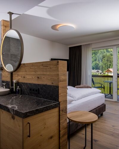 Der große Marmorwaschtisch, das Doppelbett und die Glasfront zur Terrasse des luxuriösen Chalets des Das Hintersee im Salzkammergut