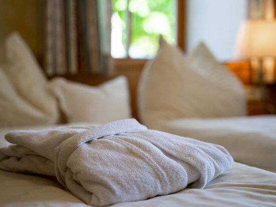 Ein Bademantel auf dem frisch gedeckten Doppelbett