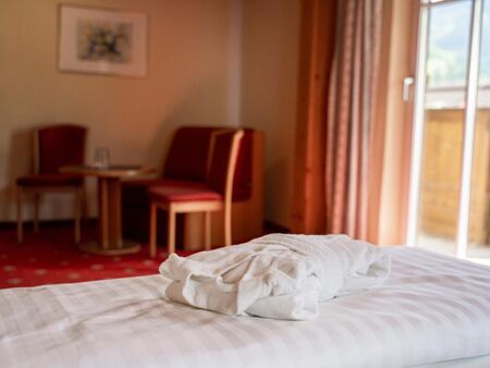 A bath towel on the double bed of the Sonnberg double room, in the background the sitting area and the access to the balcony