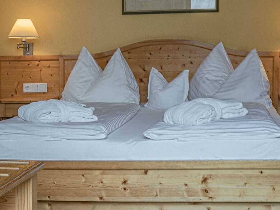 Ein Doppelbett aus hellem Holz mit frisch bezogener Bettwäsche