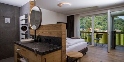 The large marble washbasin, the double bed and the glass front to the terrace of the luxurious chalet of Das Hintersee in Salzkammergut, Austria