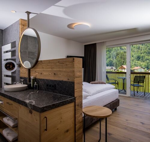 The large marble washbasin, the double bed and the glass front to the terrace of the luxurious chalet of Das Hintersee in Salzkammergut, Austria