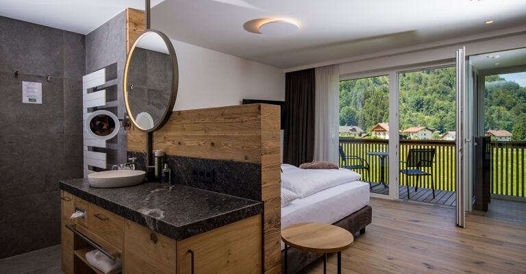 The large marble washbasin, the double bed and the glass front to the terrace of the luxurious chalet of Das Hintersee in Salzkammergut, Austria