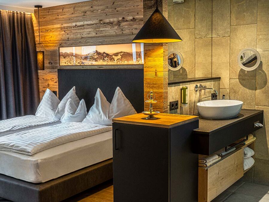 Das gemütliche Doppelbett und ein teil des Bads im Apartment Anzenberg