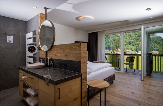 The large marble washbasin, the double bed and the glass front to the terrace of the luxurious chalet of Das Hintersee in Salzkammergut, Austria