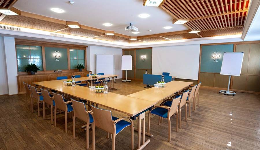 A conference room with a speaker's lectern at the front and the remaining tables and chairs arranged in a U formation