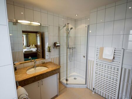 Das weiß geflieste Bad mit geräumiger Dusche