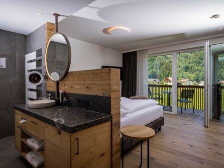 The large marble washbasin, the double bed and the glass front to the terrace of the luxurious chalet of Das Hintersee in Salzkammergut, Austria