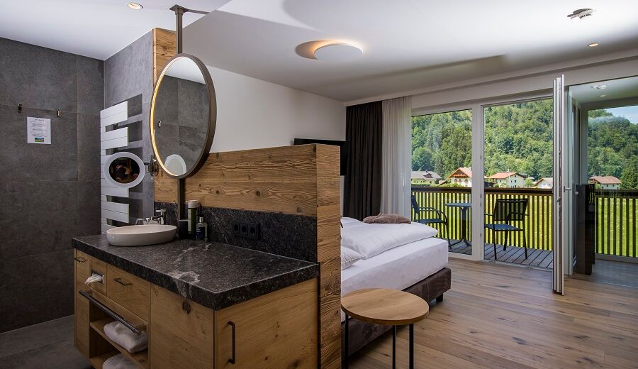 The large marble washbasin, the double bed and the glass front to the terrace of the luxurious chalet of Das Hintersee in Salzkammergut, Austria