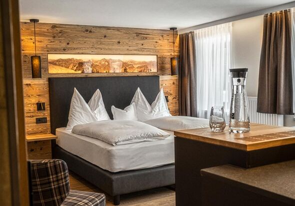 The cosy double bed with stylish wood panelling on the wall