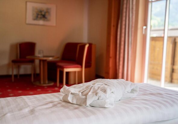 A bath towel on the double bed of the Sonnberg double room, in the background the sitting area and the access to the balcony