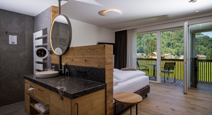 The large marble washbasin, the double bed and the glass front to the terrace of the luxurious chalet of Das Hintersee in Salzkammergut, Austria