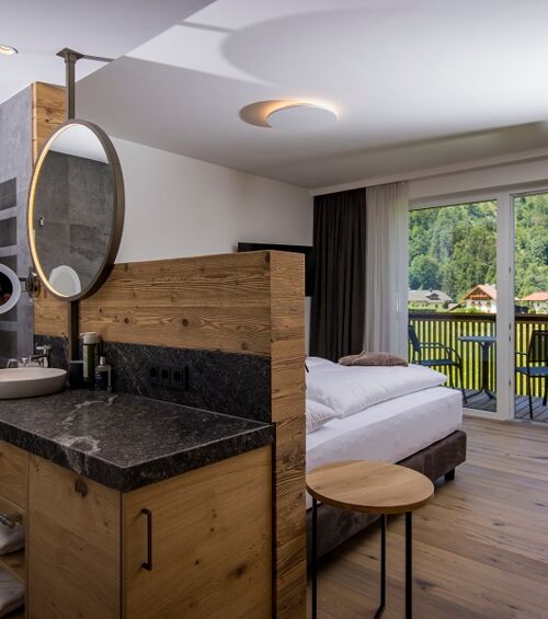 The large marble washbasin, the double bed and the glass front to the terrace of the luxurious chalet of Das Hintersee in Salzkammergut, Austria