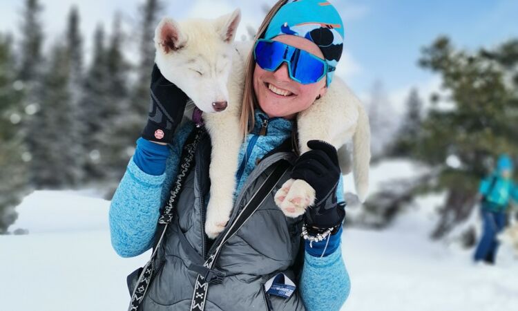 Eine Frau die einen Husky auf der Schulter hat.