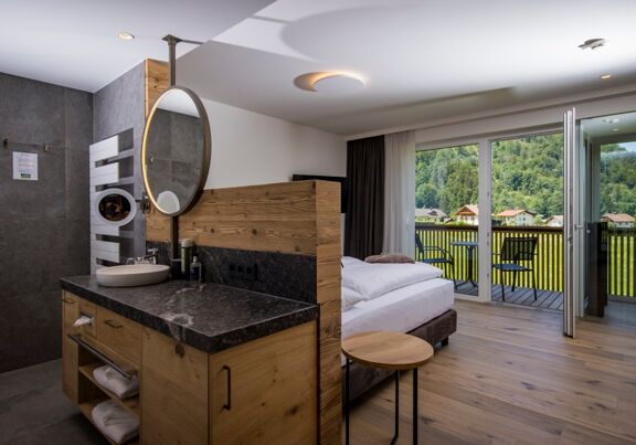 The large marble washbasin, the double bed and the glass front to the terrace of the luxurious chalet of Das Hintersee in Salzkammergut, Austria