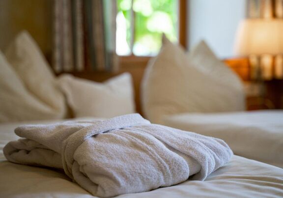 Ein Bademantel auf dem frisch gedeckten Doppelbett