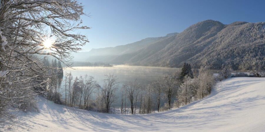 A beautiful winter landscape with sunshine and a winter hiking trail around the Hintersee in the Salzkammergut.
