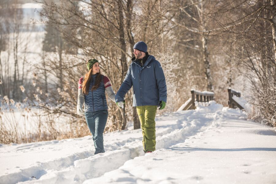 A couple enjoys hiking through the snowy landscape on a winter hiking trail in Salzburg. © SalzburgerLand Tourismus Michael Groessinger